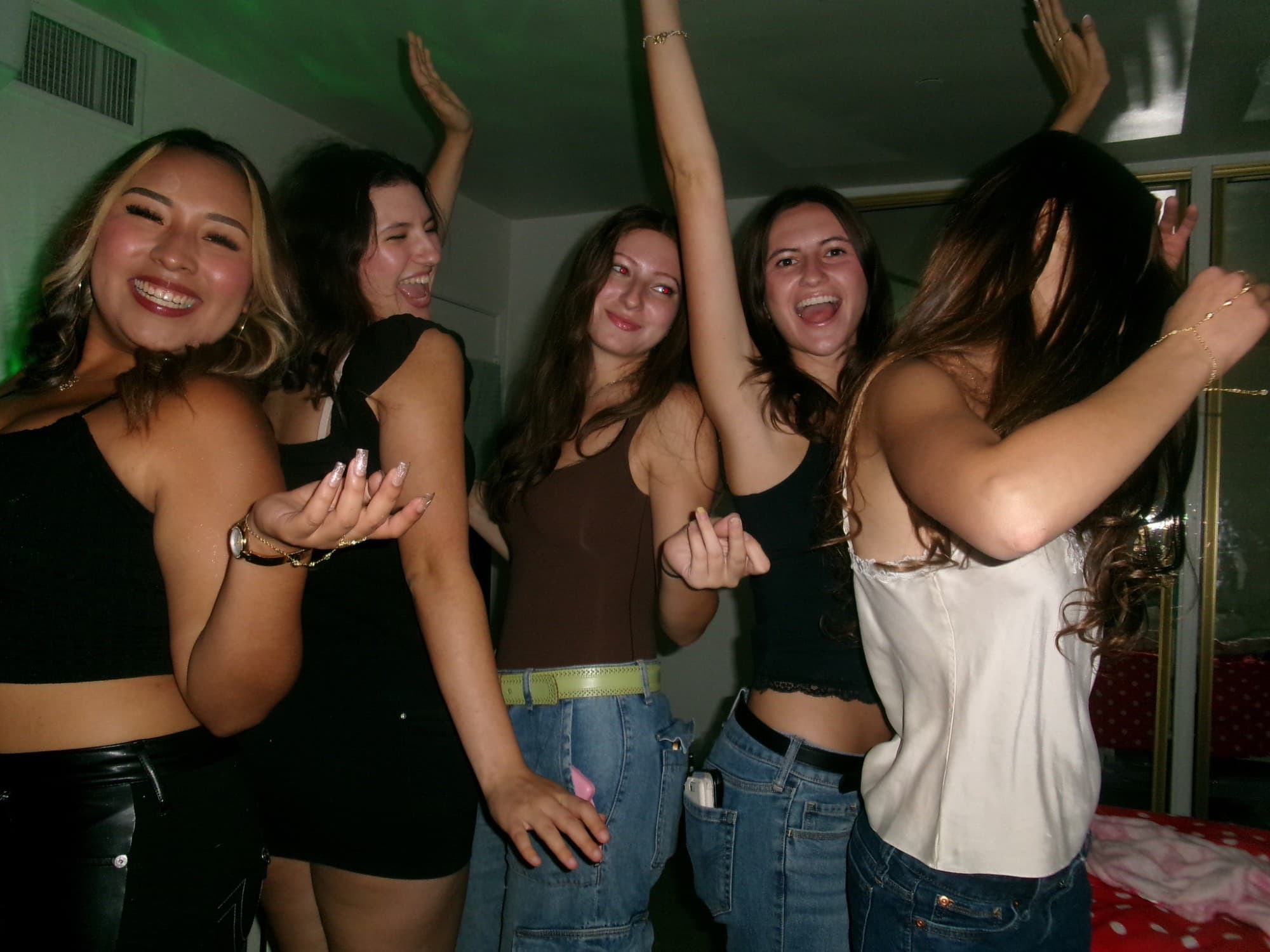 Five friends dancing and laughing together at a party